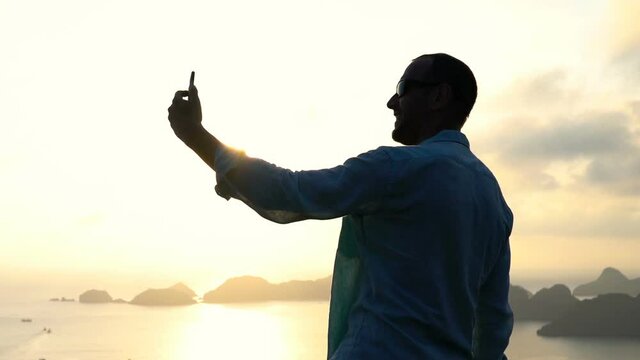 Man taking selfie photo of Ha Long Bay in Vietnam during sunset