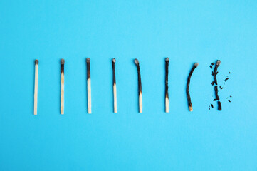 Different stages of burnt matches on light blue background, flat lay
