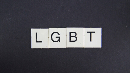 Word LGBTQ from white letters on black paper background board. Scrabble elements like crossword