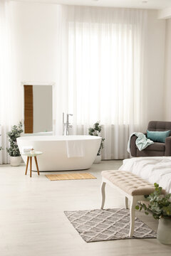 Stylish light apartment interior with white bathtub and bed © New Africa