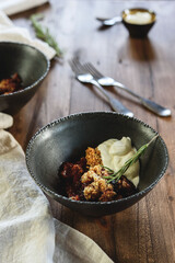 Homemade plum crumble pie with whipped cream in bowl on wooden table. Selective focus