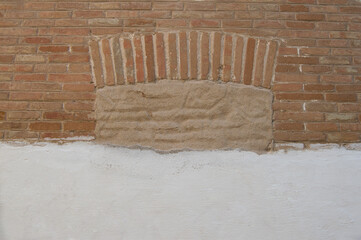 Doomed window in brick isolated on brick and  brick and plastered white painted wall