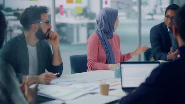 Diverse Modern Office: Successful Young Muslim Businesswoman Wearing Hijab Leads Meeting Discussion with Managers, Talks about Company Growth. Creative Digital Entrepreneurs Work on e-Commerce Project