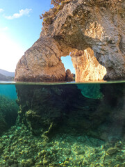 Underwater split photo of paradise sea cave arch with crystal clear emerald sea in Mediterranean destination island