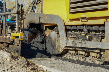 Photo of an yellow asphalt paver on the road on the street in the city