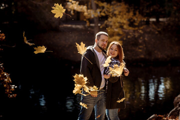 Young people man and woman throw up autumn leaves in autumn in the park during leaf fall