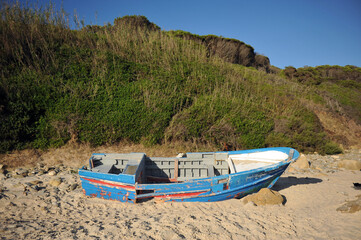 Abandoned small wooden boat on a beach near Tarifa, coast of Andalusia, Spain. These boats called "patera" are used to cross the Strait of Gibraltar by migrants from Africa to southern Europe. 