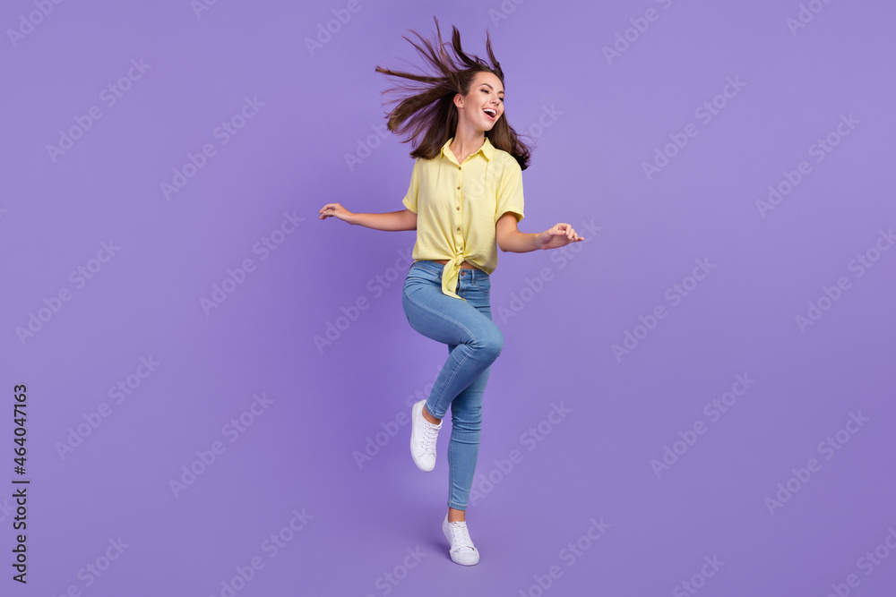 Poster full length photo of cute millennial brunette lady clubbing wear yellow top jeans sneakers isolated 