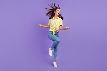Fototapeta na wymiar Full length photo of cute millennial brunette lady clubbing wear yellow top jeans sneakers isolated on purple color background