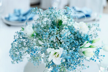 Wedding decor with beautiful flowers. Close up of blue gypsophila and white eustoma in a bouquet. Beautiful festive table decorated with bouquet of flowers. Selective focus