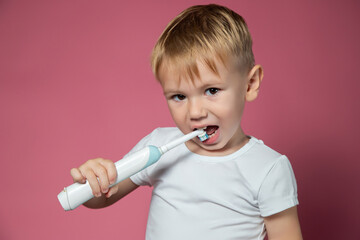 Smiling caucasian little boy cleaning his teeth with electric sonic toothbrush