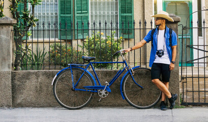 Obraz premium Tourist standing on the street next to a blue bicycle. travel concept.