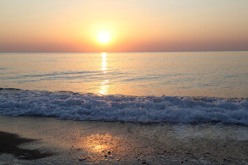 Sunrise over the sea and the wave near the coastline photographed at a long exposure