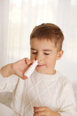 Little boy spraying medicine in nose, nose drops. Toddler child using nasal spray. Runny nose,...