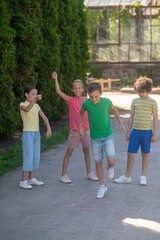 Boy jumping with raised leg and joyful friends