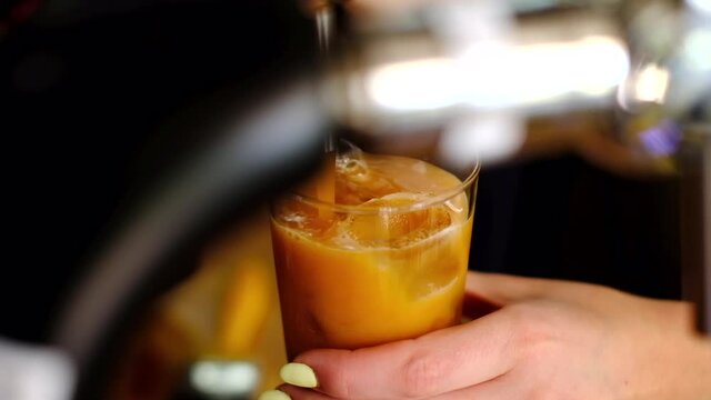 Barista pouring a nitro cold brew coffee into a glass full of ice