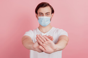 Portrait of serious guy wear respirator mask hand show stop lockdown sign on pink background