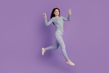 Fototapeta na wymiar Full size profile side photo of young cheerful girl jumper show peace v-sign go isolated over purple color background