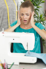 worried dressmaker looking at sewing machine