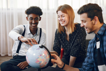 Multi ethnic friends looking at globe at home
