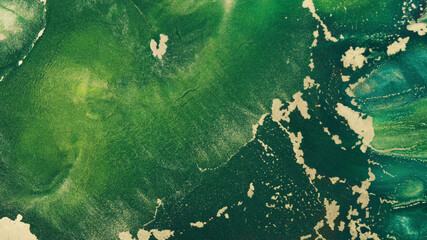 Gold green ink abstract, close-up. Shiny art dynamic green tide fluid paints. Texture of golden...