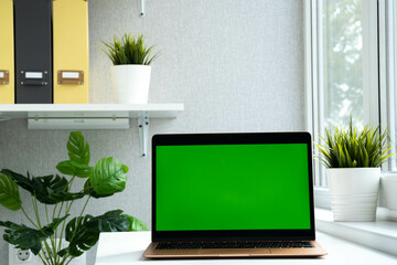 Morden laptop green screen. Chroma key green screen computer set up for work on desk at home or office, technology concept. Notebook empty for advertisement.