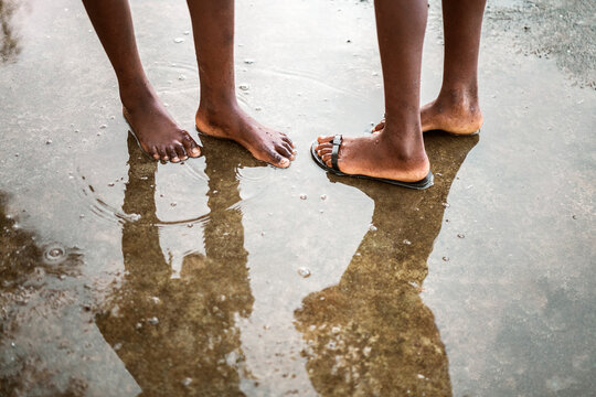 Black barefoot people standing in puddle on street