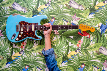 Guitar shown against wall with colorful paintings