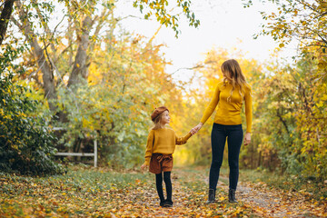 Obraz premium Young mother with her little daughter in an autumn park
