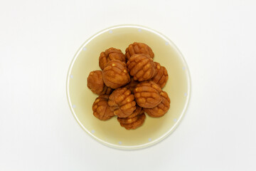 Small walnut-flavored cakes in the size and shape of a walnut on the plate. Isolate on white background. Top view.
