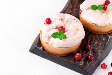 Small meringue pie with fruit and berry curd on shortcrust pastry served on the wooden board. Portion sized dessert