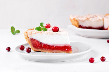Meringue pie piece with berry jam on shortcrust pastry served on the white plate. Exquisite dessert