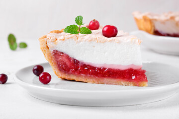 Meringue pie piece with berry jam on shortcrust pastry served on the white plate. Exquisite dessert