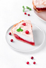 Meringue pie piece with berry jam on shortcrust pastry served on the white plate. Exquisite dessert