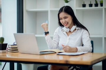 Online Education For Asian Young Women. Student Happy Arabic Girl In Headscarf And Headset Studying With Laptop At Home, Taking Notes While Watching Webinar