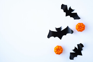 Halloween white background with black bats and orange pumpkins. View from above. Holiday decorations concept. Copy space, top view, flat lay. DIY