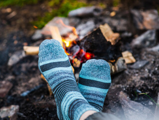 Traveler warming his feet in socks near bonfire
