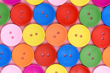 Vivid colored wooden sewing buttons pattern. Bright multicolored round buttons in rows on a pink...