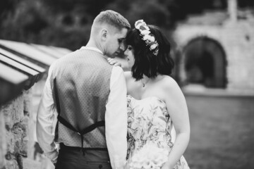 Fototapeta na wymiar Romantic, fairytale, happy newlywed couple hugging and kissing in a park, trees in background