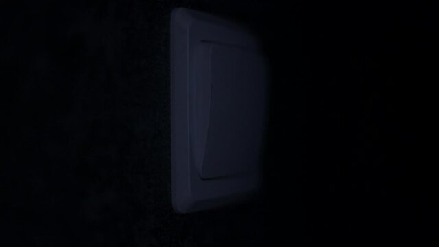 A Man's Hand Presses A Switch On The Wall And Turns Off The Light