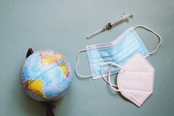 International tourism 2022 during coronavirus covid-19 pandemic concept photo. Globe, medical masks and syringe. Vaccination for travel