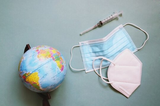 International tourism 2022 during coronavirus covid-19 pandemic concept photo. Globe, medical masks and syringe. Vaccination for travel