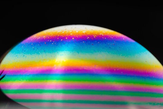 soap bubble. Close-up. Black background. Bright colors. Side view. A high resolution. Imitation of an unknown planet. Children's entertainment. Science fiction. © parianto