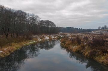 The first snow in October lies on the banks of the river