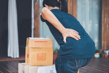 Woman with backache while lifting box.