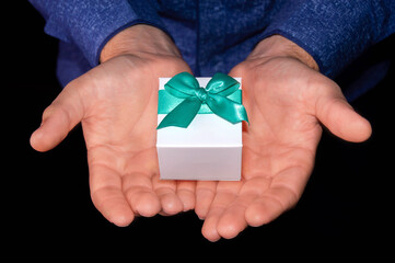 man holding a small white gift in two hands. Holiday, wedding concept