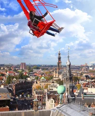 Fototapeten People on red seesaw swinging high in the air space against beautiful blue sky above the town. Amsterdam. Netherlands. Inspiration, love and dreams © Alexey Protasov