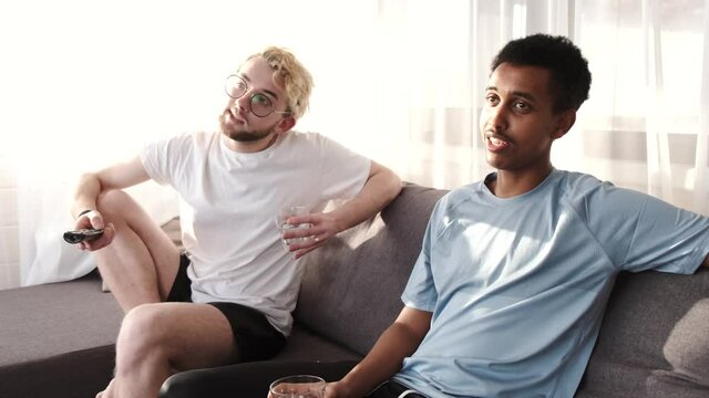 Male friends watching tv together in a bright room