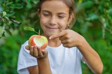 The child eats an apple in the garden. Selective focus.