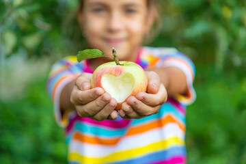 The child eats an apple in the garden. Selective focus.